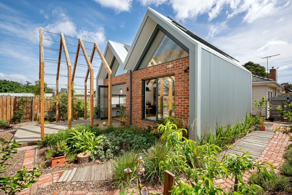 Immagine di un giardino design esposto in pieno sole dietro casa con pavimentazioni in mattoni e recinzione in legno