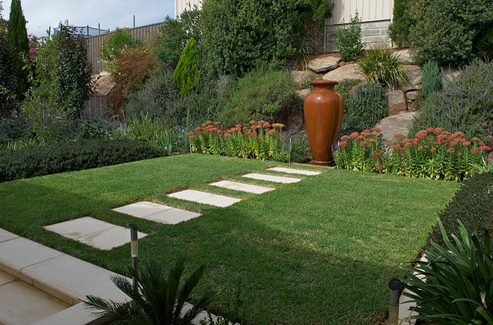 Foto di un piccolo giardino xeriscape tradizionale esposto a mezz'ombra dietro casa in primavera con pavimentazioni in cemento e un muro di contenimento