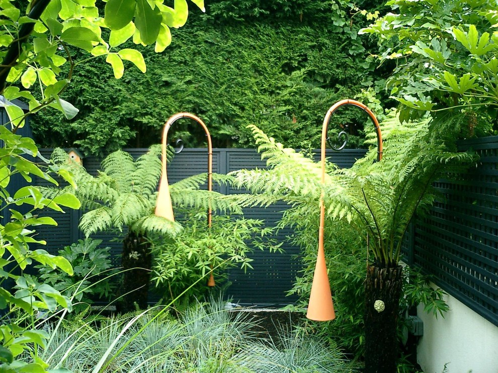Réalisation d'un petit jardin à la française arrière design avec un foyer extérieur.