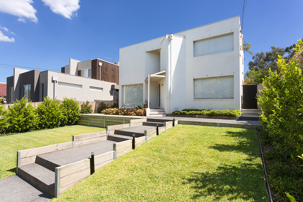 Immagine di un giardino minimalista di medie dimensioni e davanti casa con un muro di contenimento e pavimentazioni in cemento