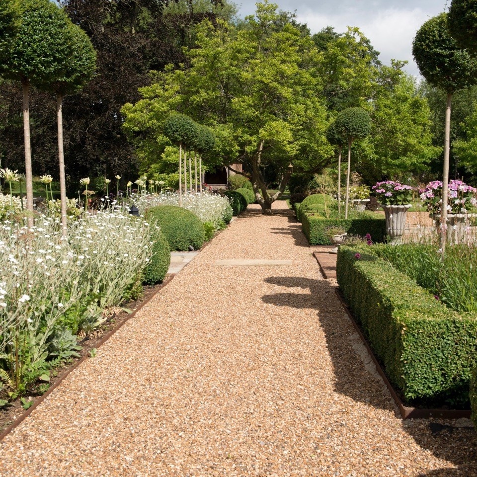 Immagine di un grande giardino formale classico esposto in pieno sole dietro casa in estate con un ingresso o sentiero e ghiaia