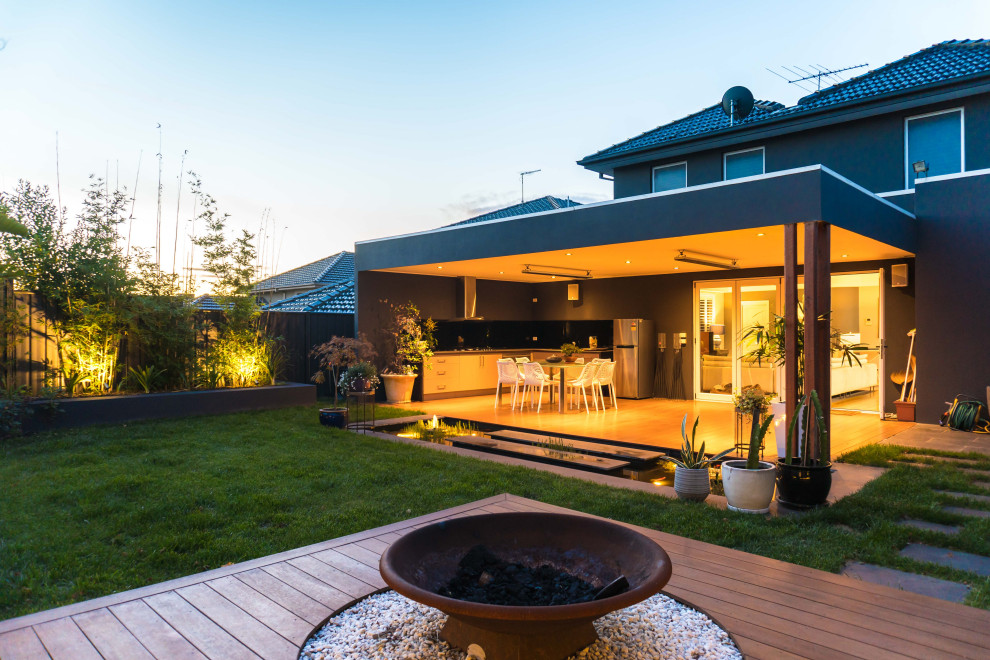 This is an example of a medium sized world-inspired back formal full sun garden for autumn in Melbourne with a fire feature and decking.