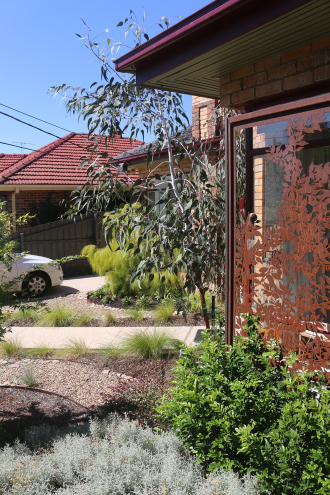Medium sized modern front xeriscape full sun garden in Melbourne with gravel.