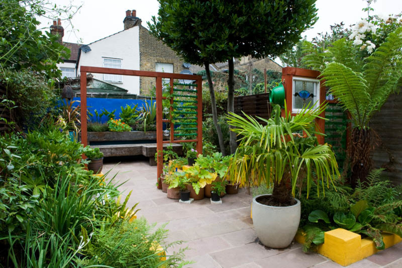 Imagen de jardín tradicional pequeño en patio trasero con jardín francés, exposición parcial al sol y adoquines de piedra natural