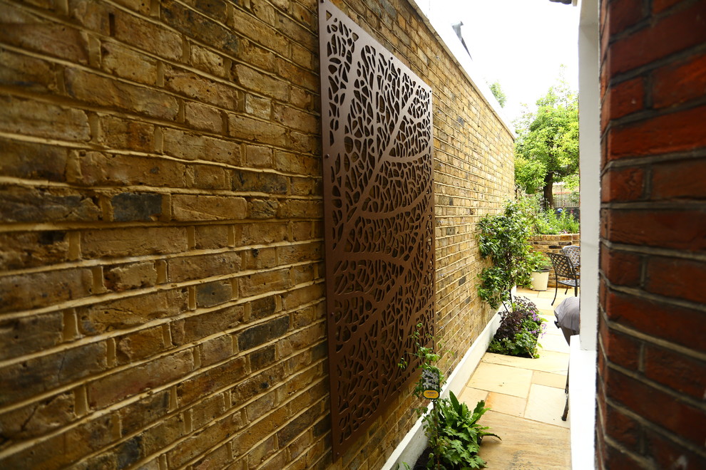 Ispirazione per un giardino formale chic esposto in pieno sole di medie dimensioni e dietro casa in estate con un muro di contenimento e pavimentazioni in pietra naturale
