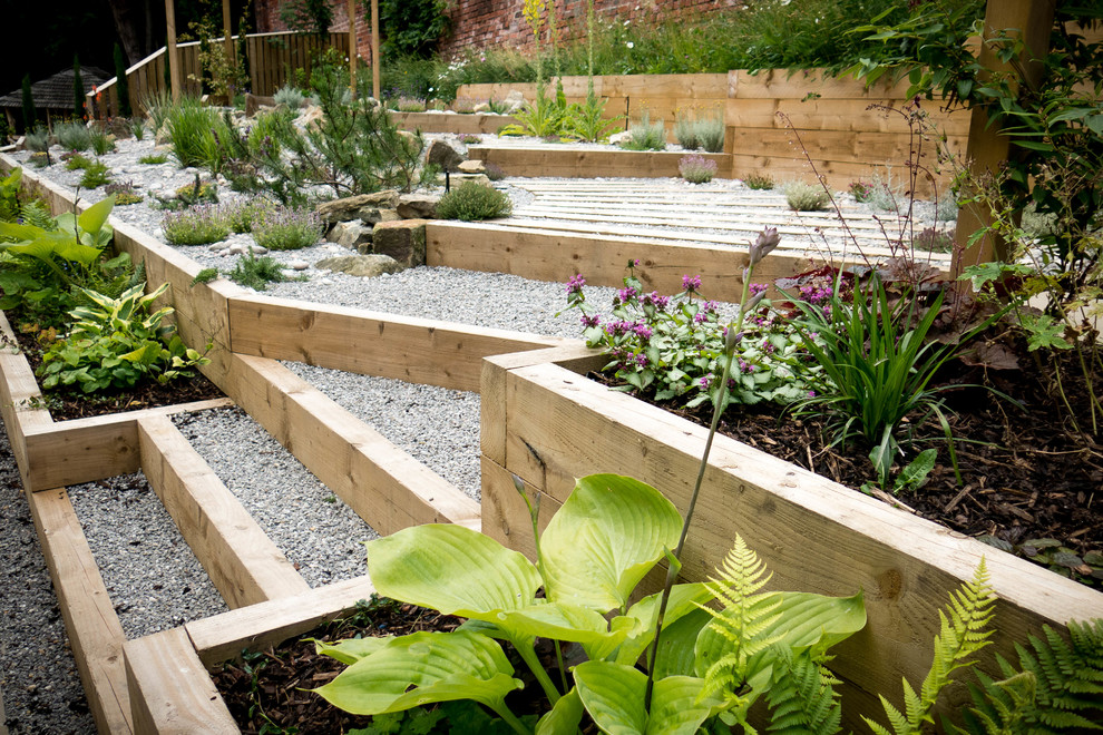 Idéer för att renovera en mellanstor funkis trädgård i skuggan på sommaren, med utekrukor och naturstensplattor