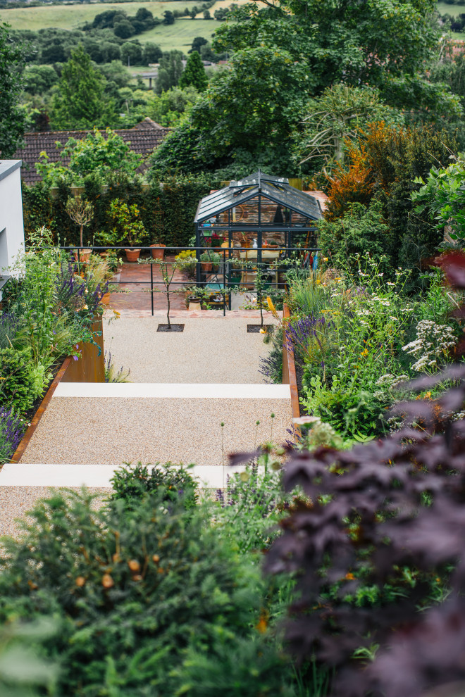 Пример оригинального дизайна: большой солнечный, летний регулярный сад на заднем дворе в скандинавском стиле с садовой дорожкой или калиткой, хорошей освещенностью и покрытием из гравия