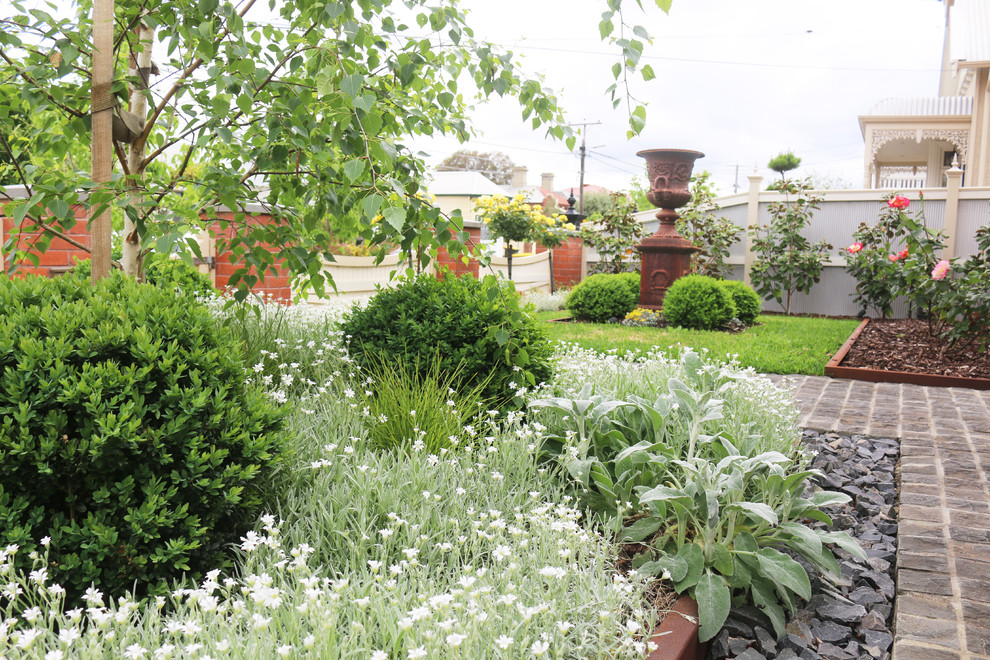 Cette image montre un jardin avant minimaliste de taille moyenne et au printemps avec une exposition ensoleillée et des pavés en pierre naturelle.