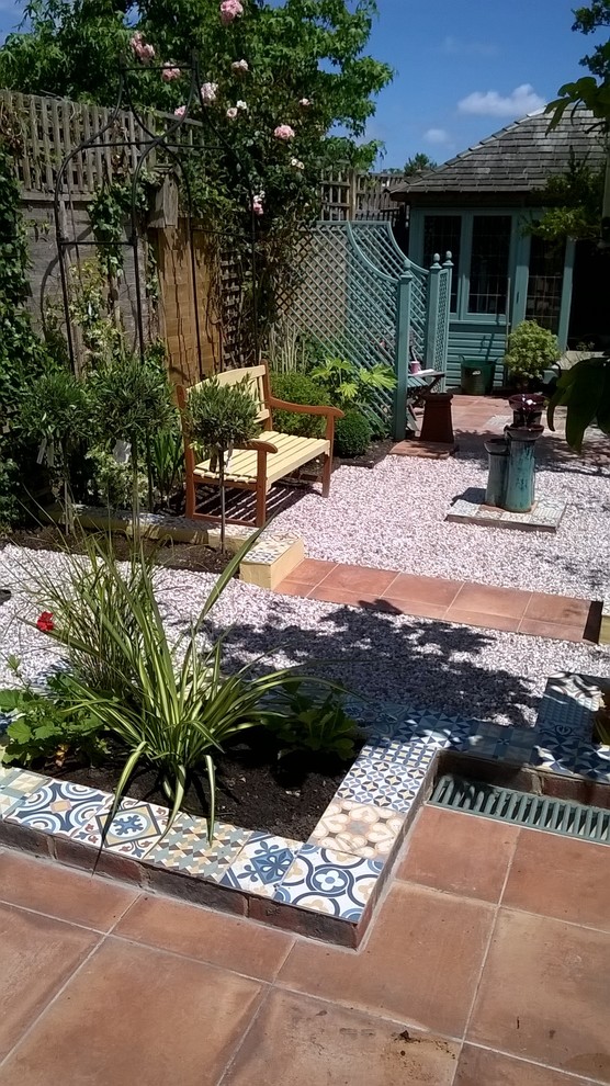 Imagen de jardín mediterráneo pequeño en verano en patio trasero con fuente, exposición parcial al sol y gravilla