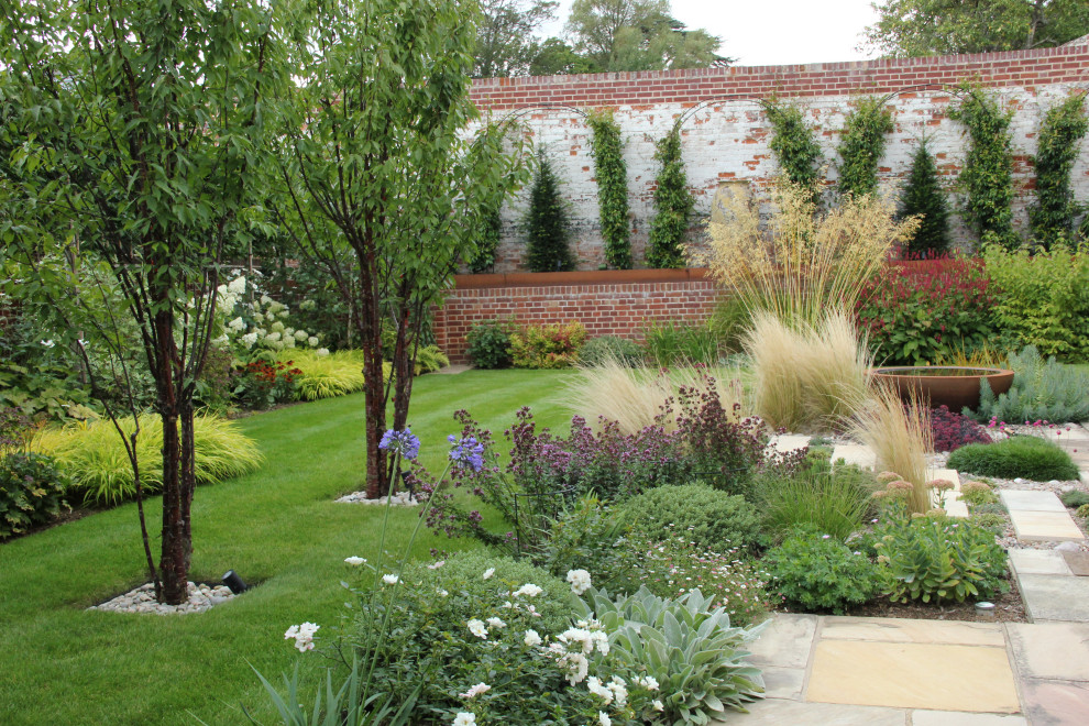Réalisation d'un jardin arrière design de taille moyenne avec une exposition ensoleillée et des pavés en pierre naturelle.