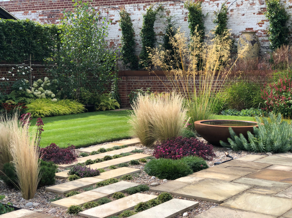 Photo of a mid-sized contemporary full sun backyard stone landscaping in Hertfordshire.