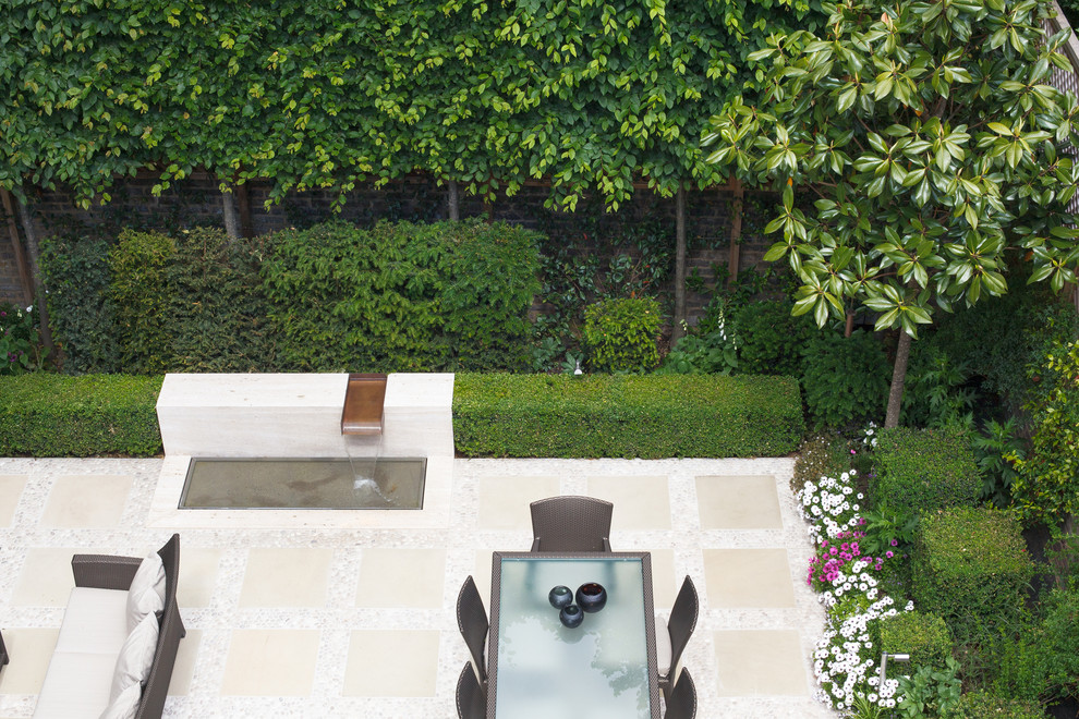 Diseño de jardín contemporáneo pequeño en verano en patio con jardín francés, fuente, exposición total al sol y adoquines de piedra natural