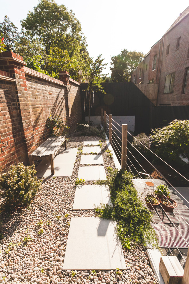 Ejemplo de jardín actual de tamaño medio en verano en patio trasero con jardín francés, muro de contención, exposición reducida al sol y adoquines de ladrillo