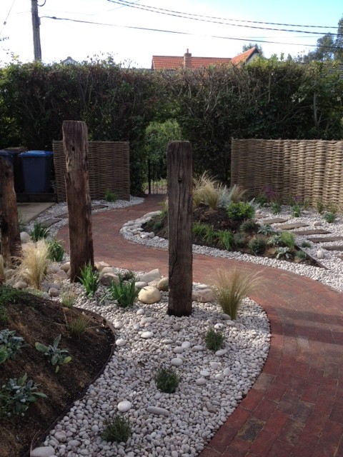 Small romantic back formal garden in Hertfordshire with a garden path and brick paving.