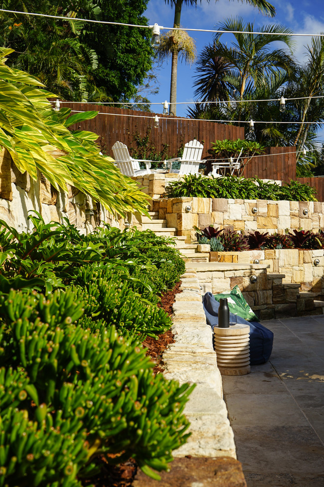 Immagine di un giardino stile marinaro dietro casa con un muro di contenimento e pavimentazioni in pietra naturale