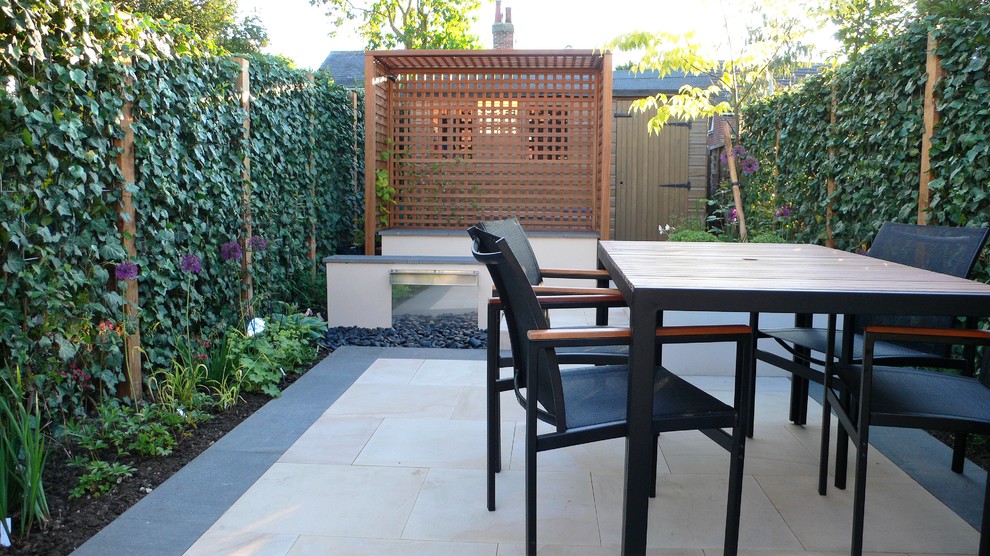 Small contemporary back fully shaded garden in Essex with natural stone paving.