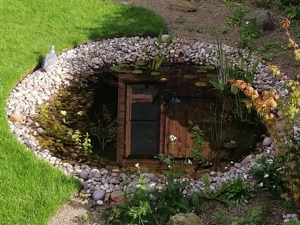Foto de jardín escandinavo de tamaño medio en verano en patio trasero con muro de contención, exposición parcial al sol y adoquines de piedra natural