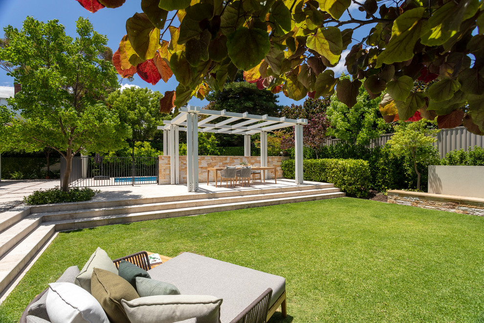 Imagen de jardín mediterráneo grande en verano en patio trasero con jardín francés, muro de contención, exposición total al sol y adoquines de piedra natural
