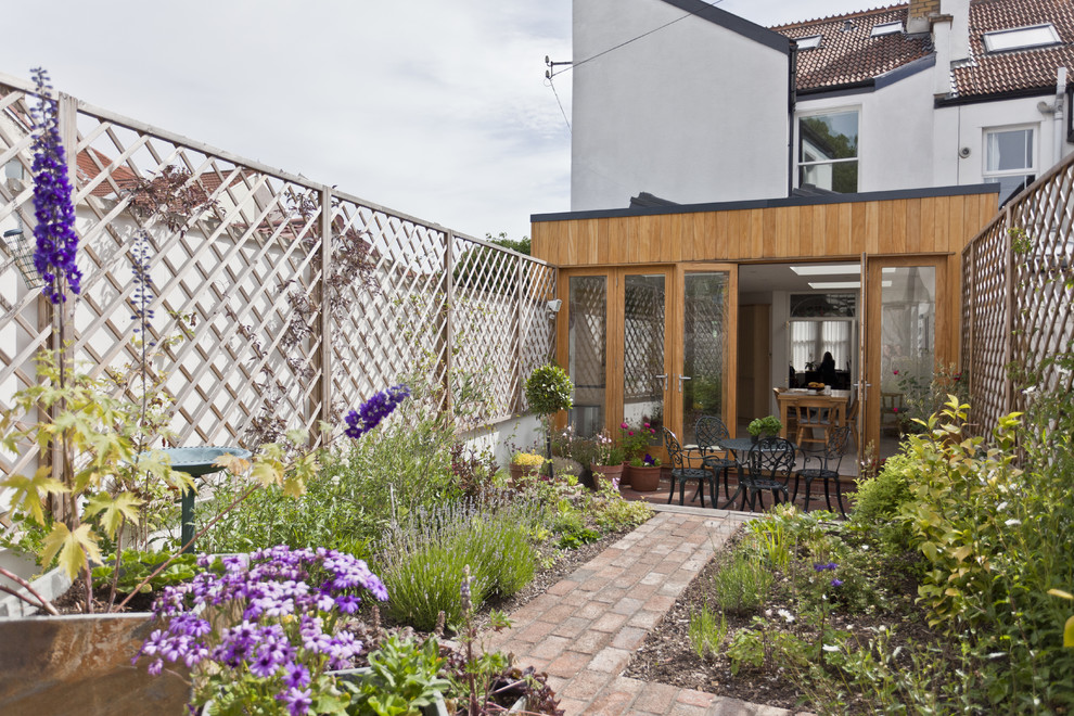 Kleiner Moderner Garten hinter dem Haus mit Pflastersteinen in Sonstige