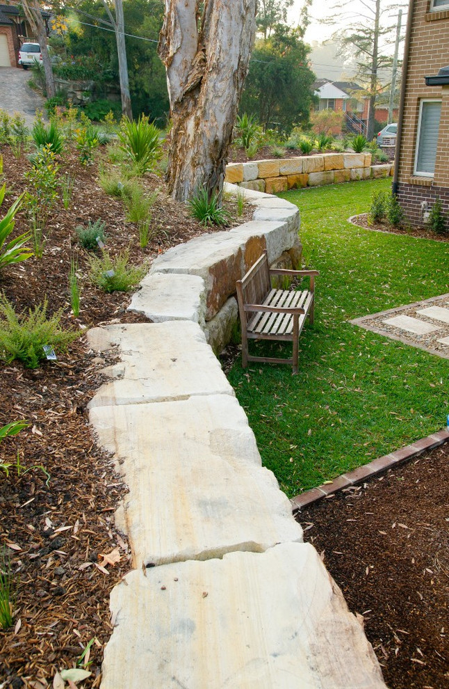 This is an example of a classic front garden in Sydney with a retaining wall and natural stone paving.