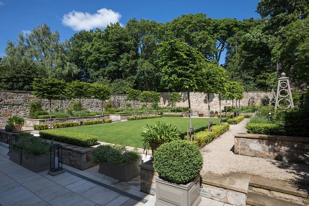 Ejemplo de jardín clásico en patio trasero con jardín francés y gravilla