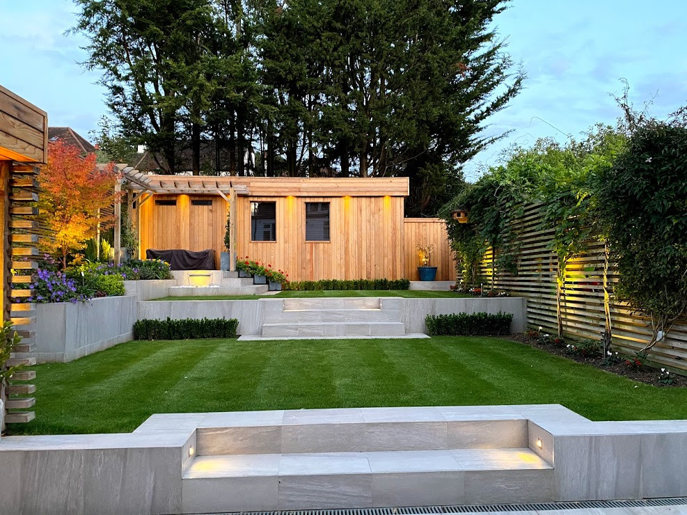 Kleiner Moderner Garten im Sommer, hinter dem Haus mit direkter Sonneneinstrahlung und Holzzaun in London