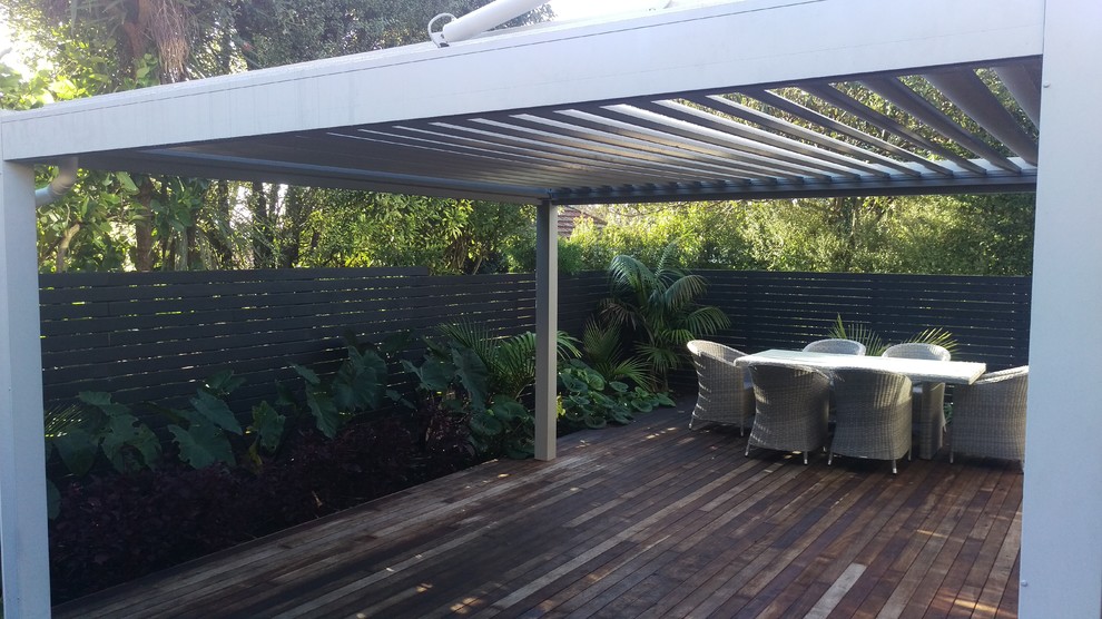 Design ideas for a mid-sized contemporary full sun backyard landscaping in Auckland with decking for winter.