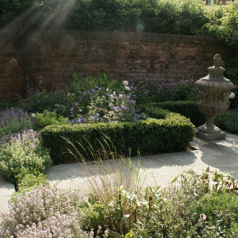 This is an example of a small traditional courtyard formal partial sun garden in Oxfordshire with natural stone paving.