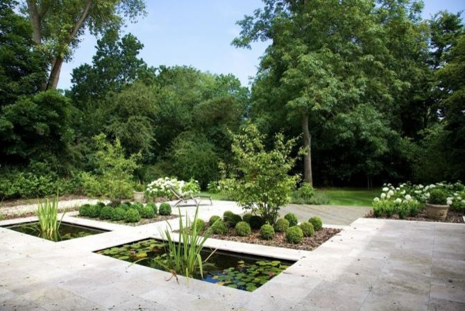 Imagen de jardín actual de tamaño medio en patio trasero con fuente, exposición parcial al sol y adoquines de piedra natural