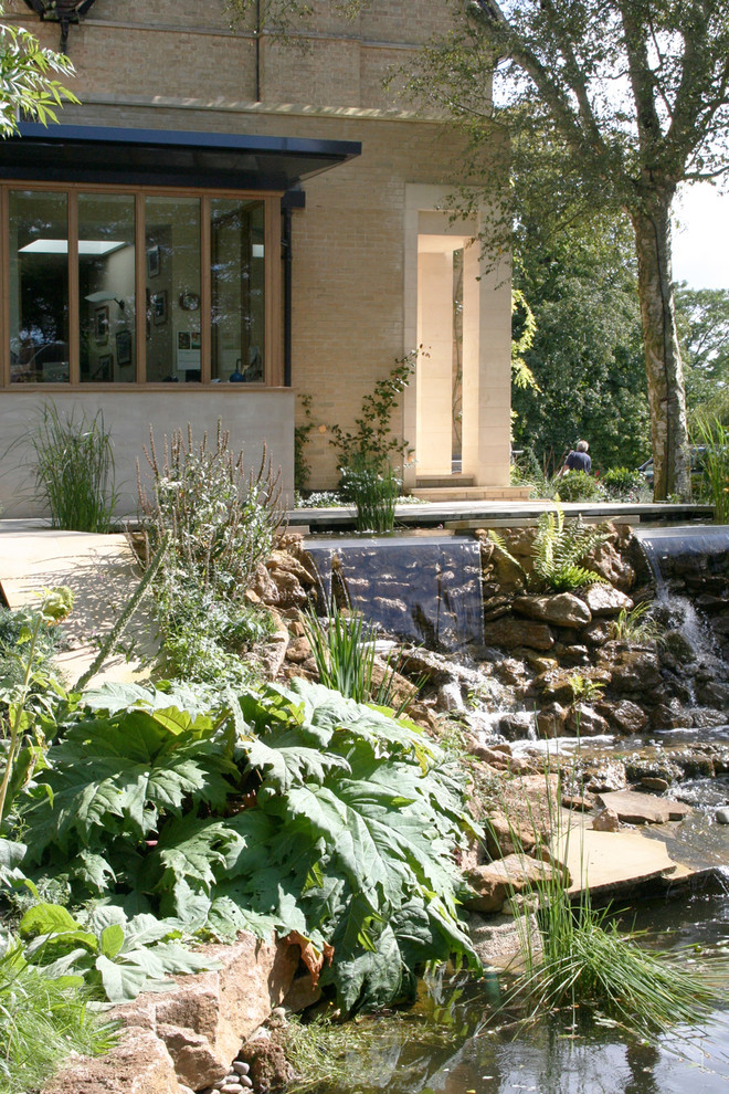 Immagine di un ampio giardino design esposto a mezz'ombra con fontane, un pendio, una collina o una riva e pavimentazioni in pietra naturale