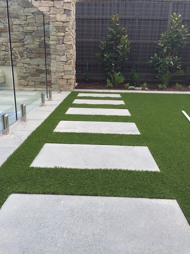 Photo of a small modern back partial sun garden for autumn in Adelaide with an outdoor sport court and natural stone paving.