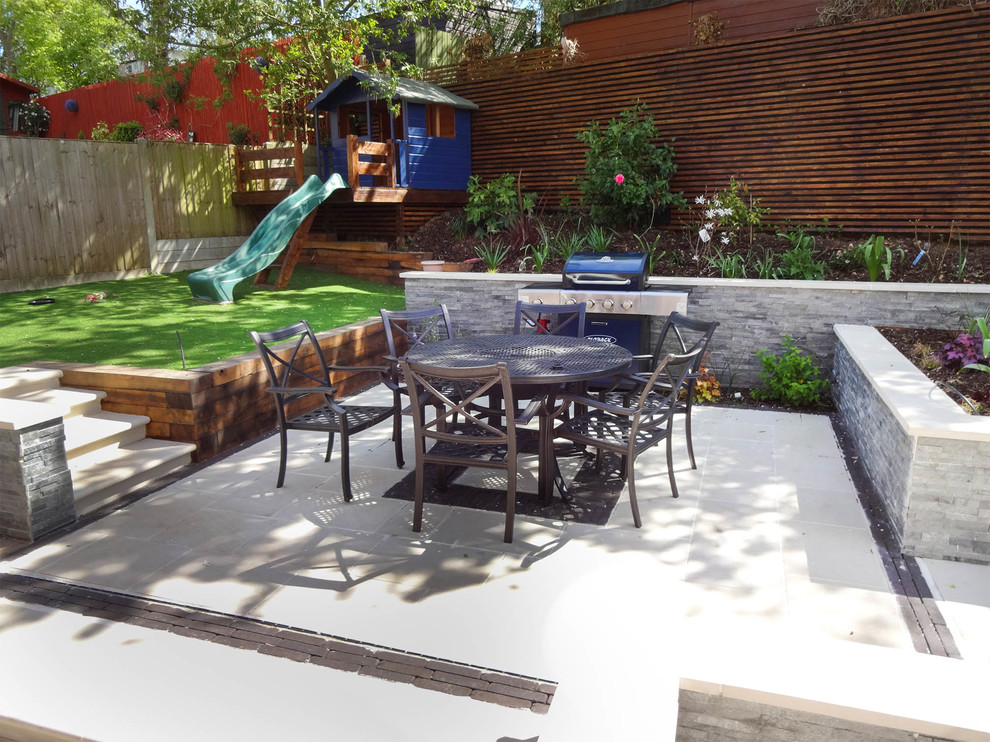 Inspiration for a medium sized contemporary back patio in Kent with natural stone paving.