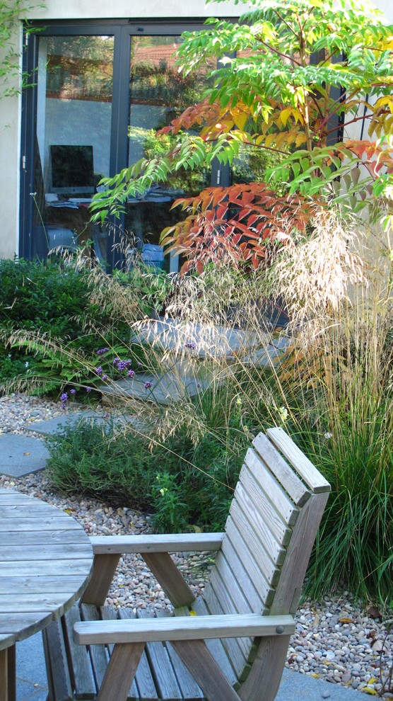 This is an example of a mid-sized contemporary partial sun backyard gravel landscaping in London for winter.