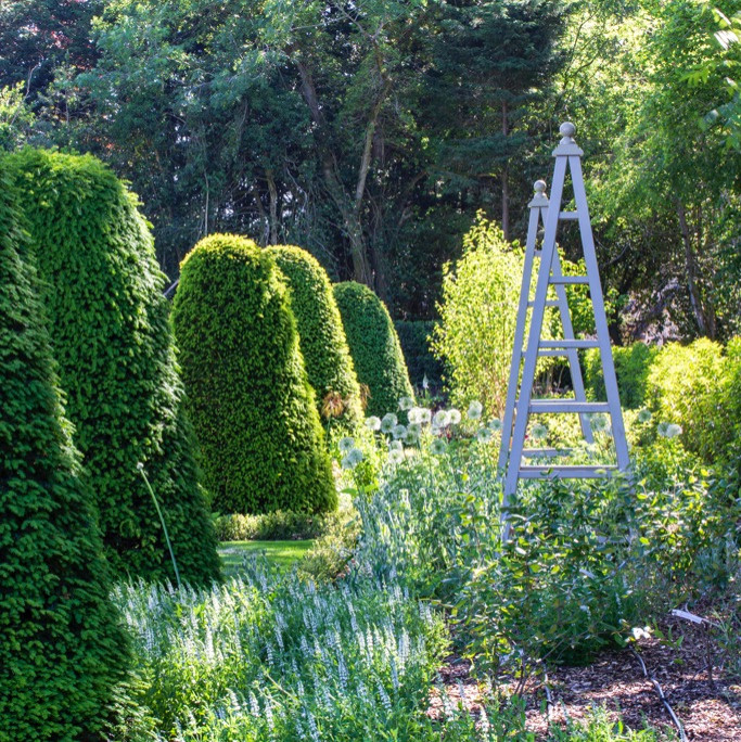 Modelo de jardín clásico extra grande en verano en patio trasero con jardín francés, parterre de flores, exposición parcial al sol y adoquines de piedra natural