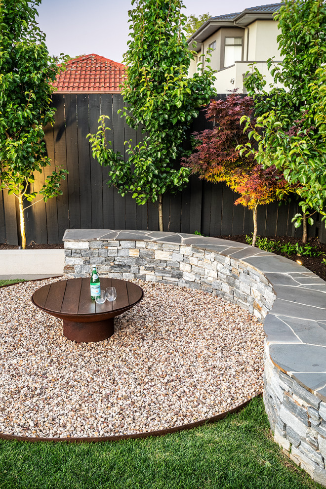 Cette image montre un jardin arrière design de taille moyenne avec un foyer extérieur et des pavés en pierre naturelle.
