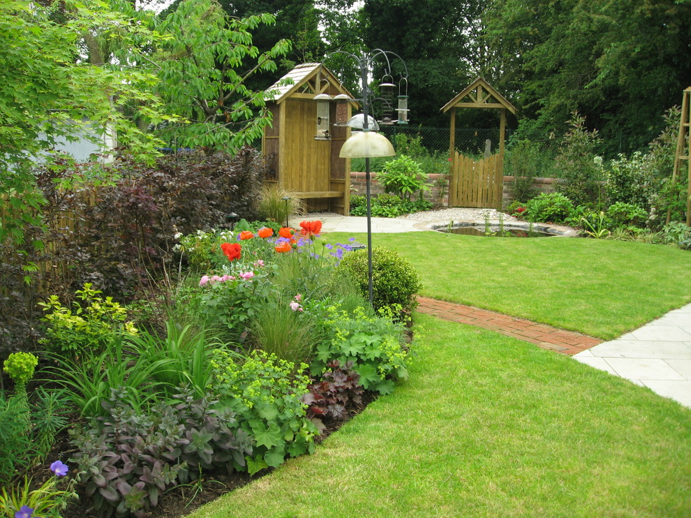 Mittelgroßer Moderner Gartenteich im Sommer, hinter dem Haus mit direkter Sonneneinstrahlung und Natursteinplatten in Manchester