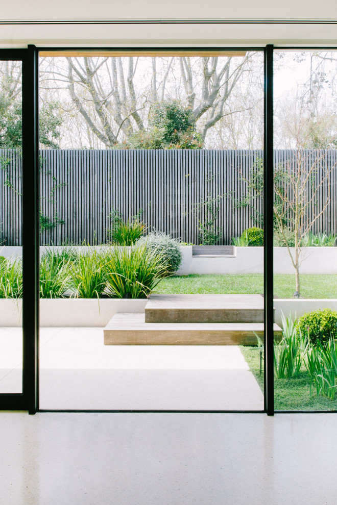Cette photo montre un grand jardin arrière moderne avec des solutions pour vis-à-vis, une exposition ensoleillée et des pavés en béton.