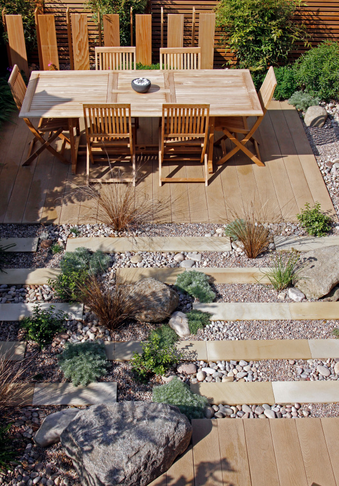 Small contemporary back formal full sun garden for summer in London with natural stone paving.