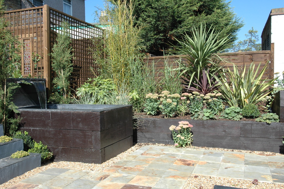 This is an example of a medium sized contemporary back formal partial sun garden in London with a water feature and natural stone paving.