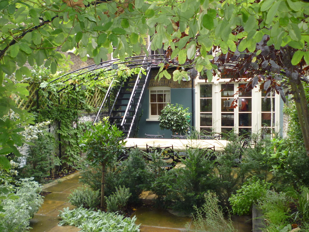 Imagen de jardín clásico pequeño en patio trasero con jardín francés, muro de contención y adoquines de piedra natural
