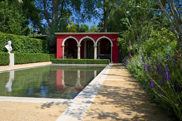 Large mediterranean courtyard full sun garden for summer in London with gravel and a pond.