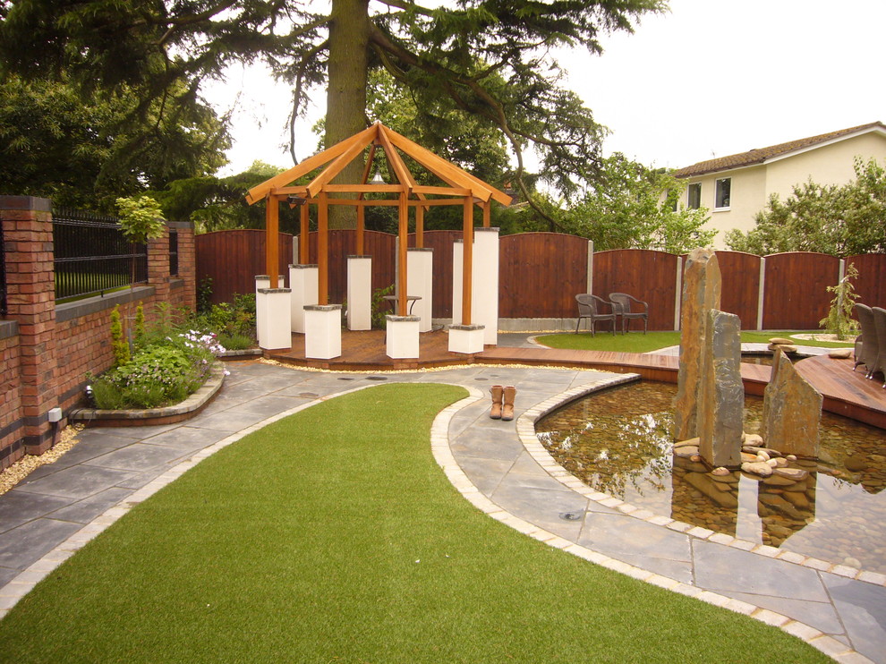 Contemporary garden in Manchester with a pond and concrete paving.