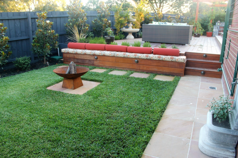 Medium sized mediterranean back formal full sun garden for winter in Melbourne with a fire feature and natural stone paving.