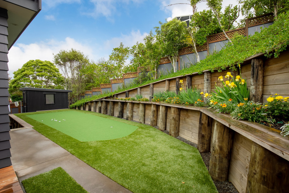 Geometrischer, Mittelgroßer, Halbschattiger Moderner Garten im Frühling, hinter dem Haus mit Spielgerät und Dielen in Auckland