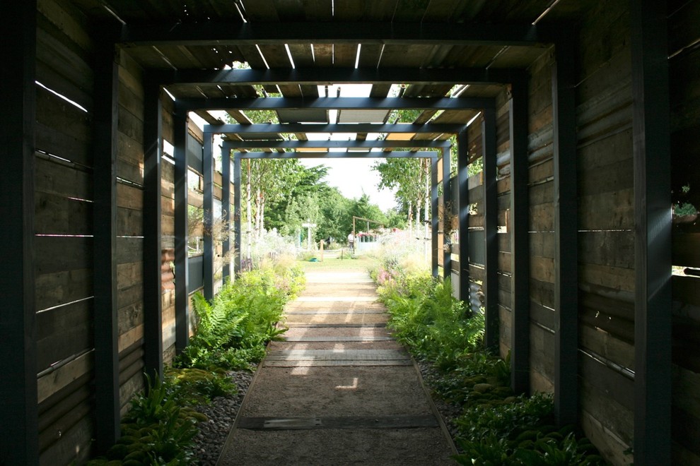 Aménagement d'un grand jardin campagne avec une exposition ombragée et des pavés en béton.