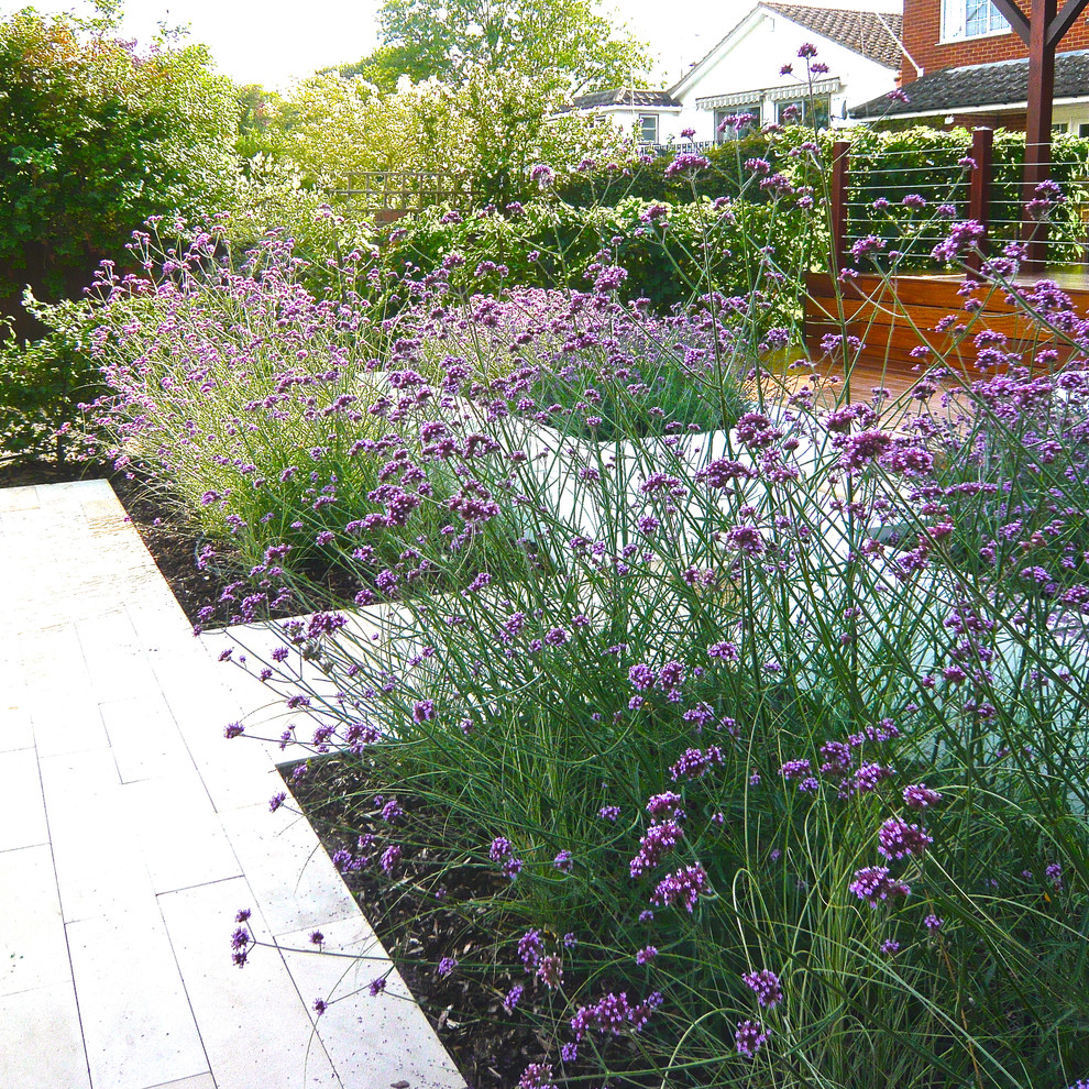 Пример оригинального дизайна: маленький солнечный, летний регулярный сад на переднем дворе в современном стиле с высокими грядками, хорошей освещенностью и покрытием из каменной брусчатки для на участке и в саду