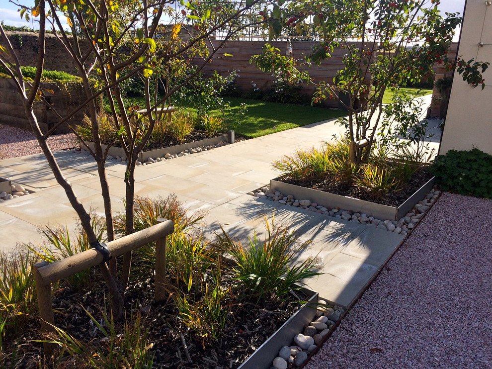 Contemporary front full sun garden in Devon with a garden path and natural stone paving.