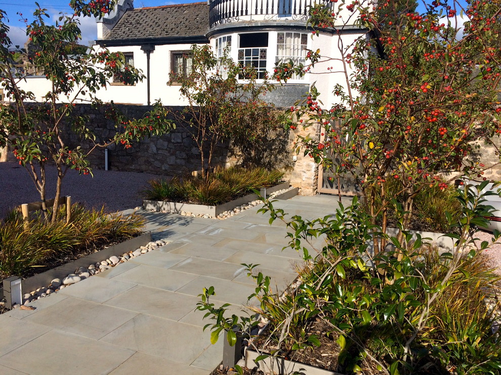 This is an example of a contemporary full sun garden in Devon with natural stone paving.