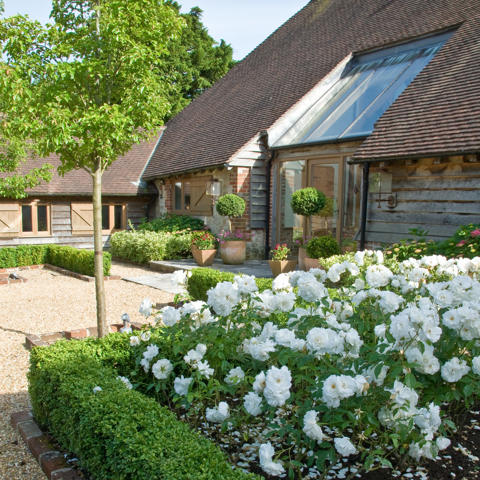Ejemplo de jardín de estilo de casa de campo grande en verano en patio con exposición parcial al sol y gravilla