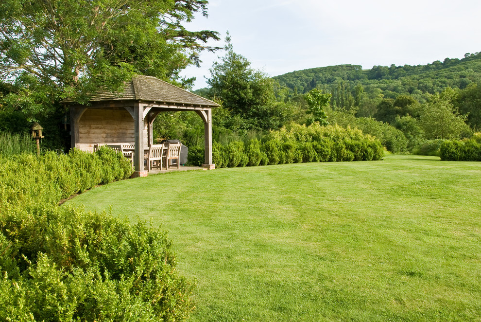 Imagen de jardín campestre grande en verano en patio trasero con exposición total al sol y adoquines de piedra natural
